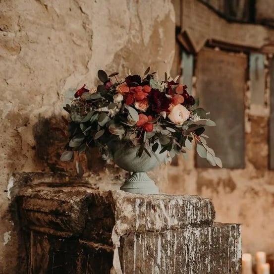 Pedestal urn arrangement in a candlelit rustic venue