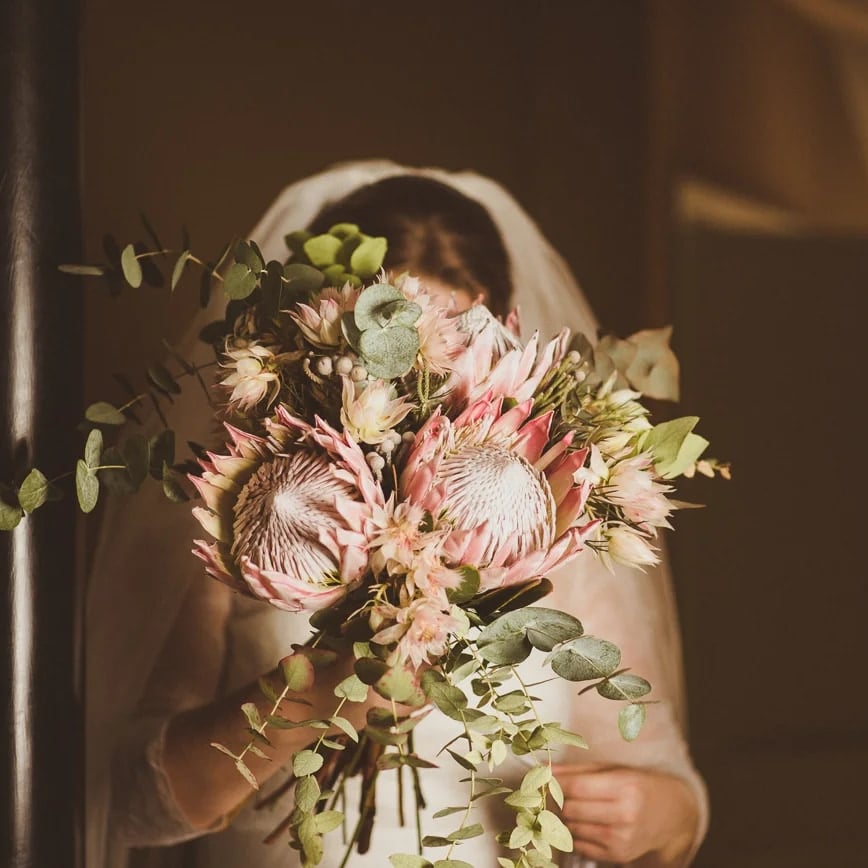 Bride holding a king protea and eucalyptus bouquet