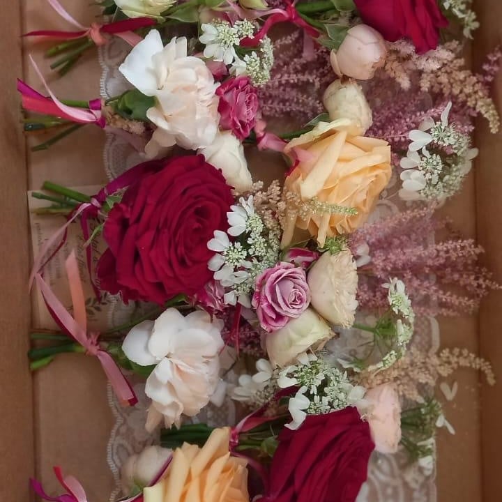 Box of hand-tied wedding buttonholes in red, blush and ivory roses