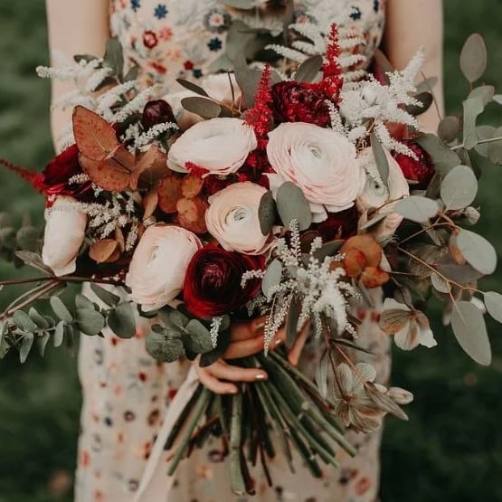 Bridesmaid holding a burgundy and blush bouquet